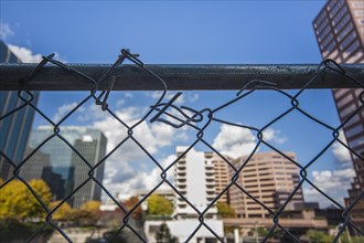 Broken chain-link fence in front of office buildings