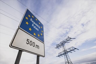 Border sign towards Poland in front of an electricity pylon