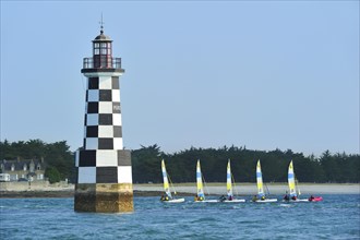 Dinghies from sailing school passing by the lighthouse Perdrix at Loctudy