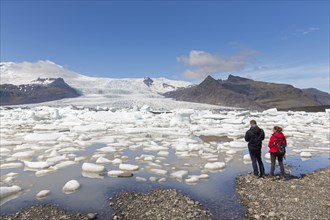 Tourists looking over the glacier lake Fjallsarlon and Icelandic glacier Fjallsjoekull