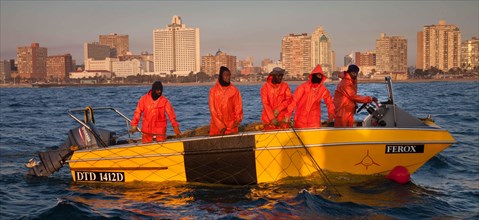 The crew of a boat sets nets to protect against sharks in the early morning off the South African city of Durban