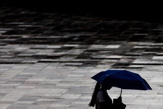 A woman with an umbrella stands out in Tirana