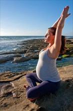 Pregnant woman doing yoga on rocks