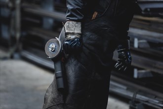 A metal worker carries a cut-off grinder