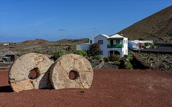 Millstones in the sand in front of white villa