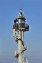 Worker wearing safety harness doing maintenance work on the Alprech lighthouse with spiralling exterior staircase near Le Portel