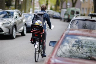 Symbolic photo on the subject of children in road traffic A toddler is sitting in a child seat on a bicycle and is being driven across a road by his mother. Berlin