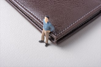 Tiny figurine of man miniature model beside a wallet
