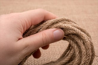 Bundle of linen rope in hand on a brown background