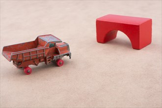 Toy car truck near a brick on a wooden background