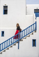 Young woman with red skirt on a staircase with blue banister