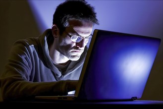 Man in his mid-forties with glasses working at night on laptop
