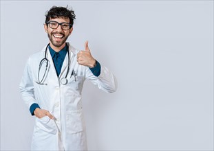 Smiling doctor giving thumb up isolated. Handsome doctor with thumb up smiling isolated. Young doctor with thumbs up gesture