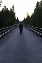 Out of focus person walking alone along a country road in the bright Nordic night in midsummer