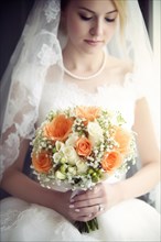 A bride in a white wedding dress holds a beautiful bridal bouquet