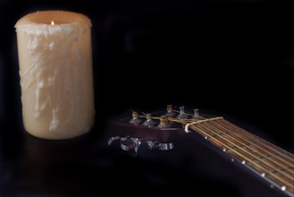 Spanish guitar neck with a candle in the background on a black background