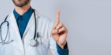 Doctor finger pointing up with text space. Unrecognizable doctor pointing up