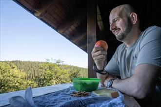 Man eating apple and looking at the forest