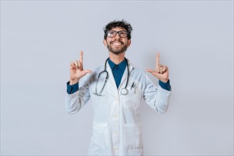 Handsome doctor pointing up. Smiling doctor pointing a promo up. Male doctor looking and pointing up isolated