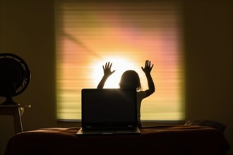Silhouette of a small child in front of a window in the backlight