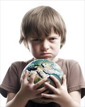 A young boy with an angry look holds a globe protectively in his hands