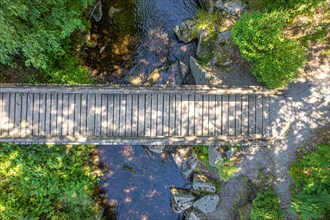 Aerial view of a wooden bridge over a small river in the forest on the hiking trail Sprollenhaeuser Hut
