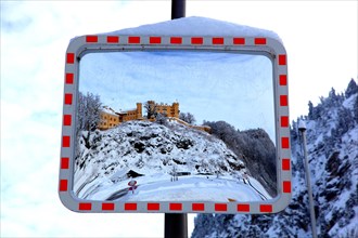 A traffic mirror shows Hohenschwangau Castle in winter