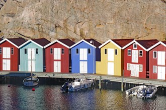 Colourful beach houses in a small harbour are overlooked by granite rocks