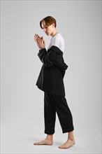Young barefoot man in black suit posing in studio