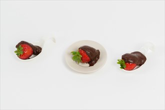 Strawberries with chocolate on a white ceramic spoon isolated on a white background