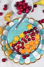 Blue fruit smoothie bowl dyed with natural spirulina powder decorated with cranberries