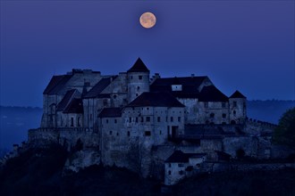 The full moon sets behind the castle in Burghausen