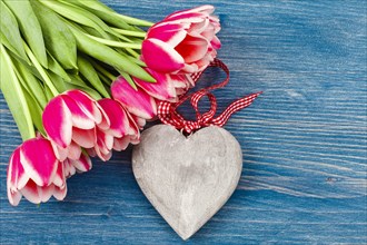 Tulips on blue background with large wooden heart