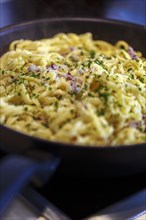 Swabian Kaesspaetzle with onions and herbs stew in a pan