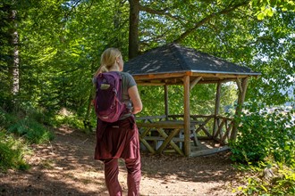 Hiking woman standing in front of wooden pavilion in the forest on the hiking trail Sprollenhaeuser Hut