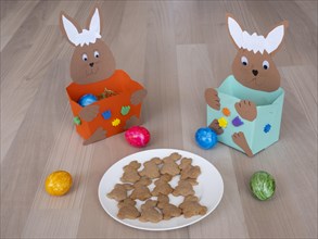 Plates of homemade Easter bunny biscuits in front of homemade Easter nests