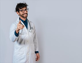 Smiling doctor pointing at you isolated. Young doctor pointing at you. Friendly doctor pointing at the camera