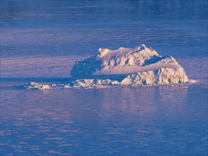 Iceberg in the frozen Kong Oscar Fjord at dawn