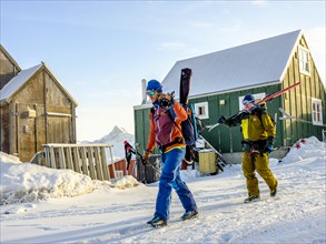 Ski mountaineers carry their skis through Tasiilaq in winter