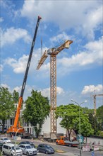 A construction crane is erected with a truck-mounted crane
