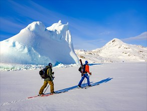 Ski mountaineer in front of iceberg in frozen Kong Oscar Fjord