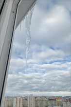 Huge icicle on the roof with a blue sky on background