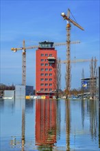Tower of the former Munich-Riem Airport with reflection and construction cranes
