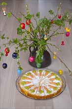 Homemade carrot cake in front of a shrub with Easter decorations