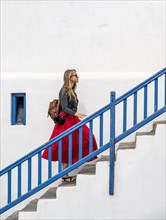 Young woman with red skirt on a staircase with blue banister