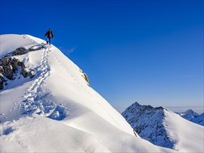 Climbers descending the snow ridge