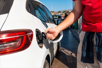 Man opening the car nozzle to refuel gasoline or diesel fuel in a white car. Concept of transportation