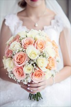 A bride in a white wedding dress holds a beautiful bridal bouquet