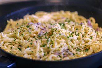Swabian Kaesspaetzle with onions and herbs stew in a pan