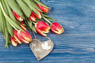 Tulips and a wooden heart with inscription In Love
